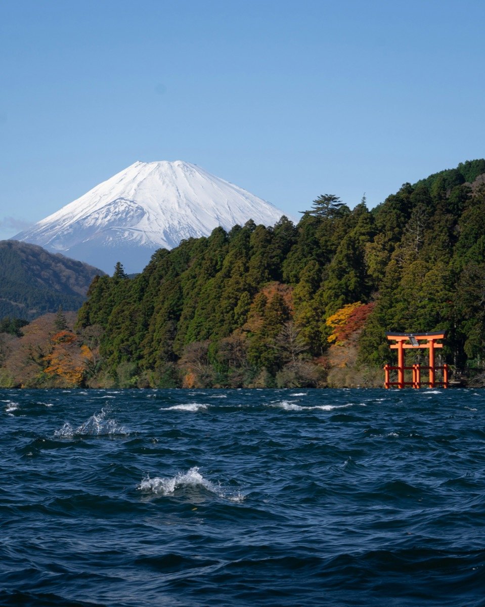 Lake Ashi in Hakone with Mt Fuji snowcapped in the background and the red torii gate of Hakone Shrine