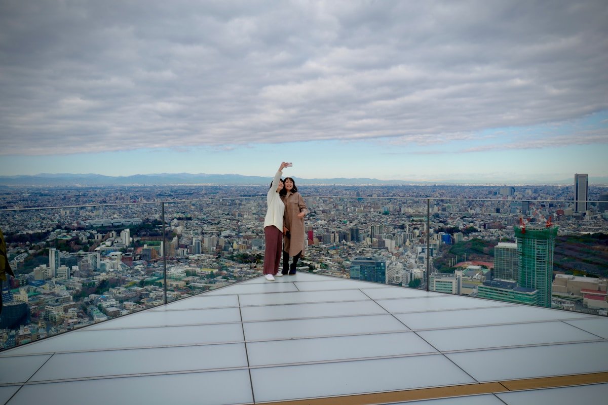 Two women taking a selfie on the open-air rooftop of Shibuya Sky observation deck, Tokyo, Japan