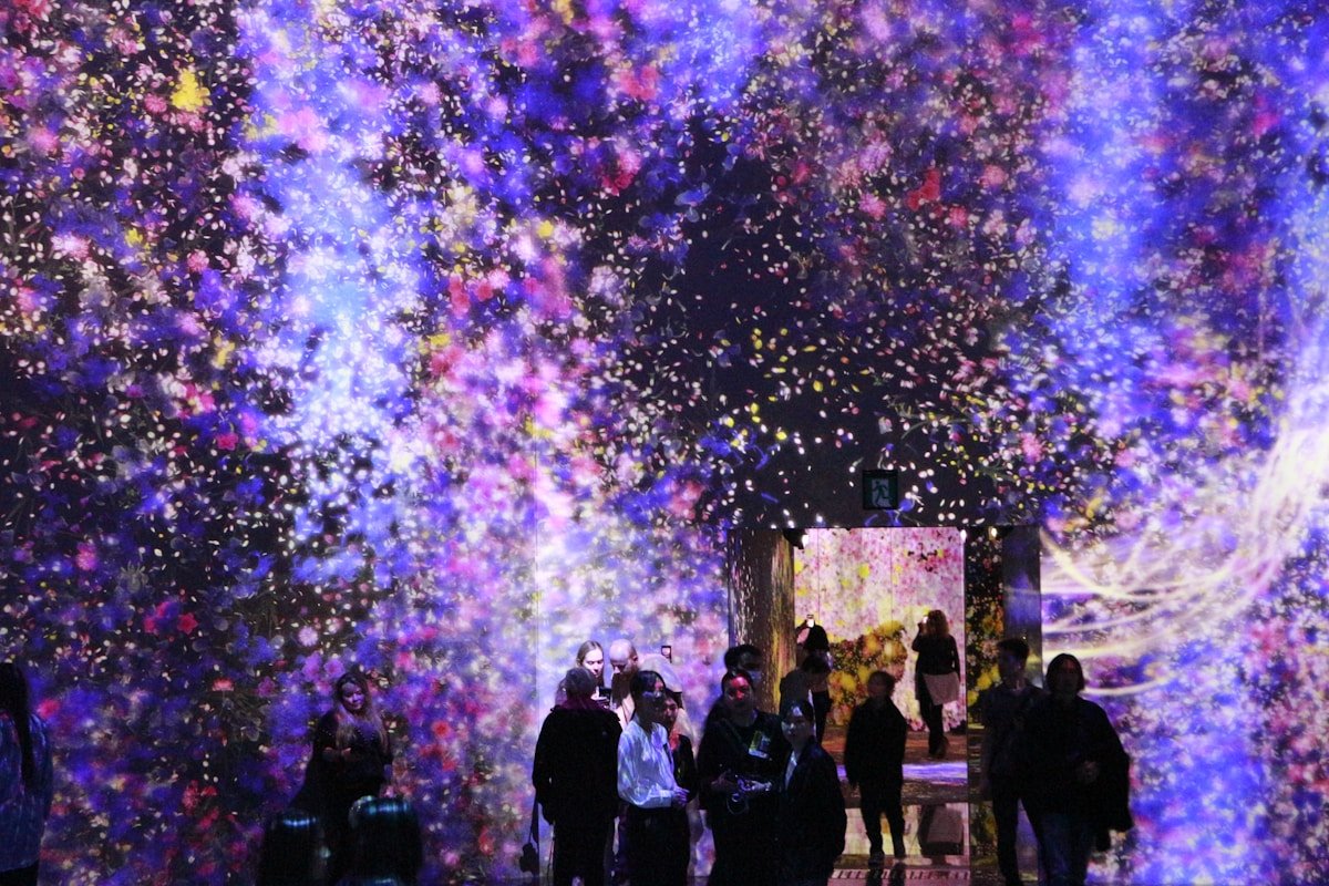 Visitors walking through a vast digital light installation at teamLab in Tokyo, Japan