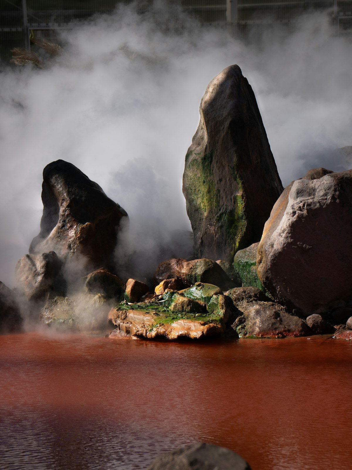 Steaming red hot spring pools with rocks and steam rising in Beppu, Japan
