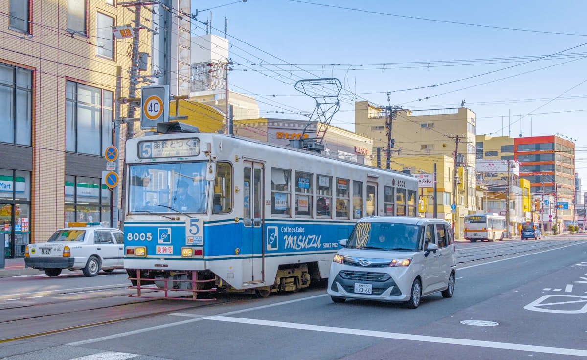 Blue and white Hakodate tram on a city street, Hokkaido Japan