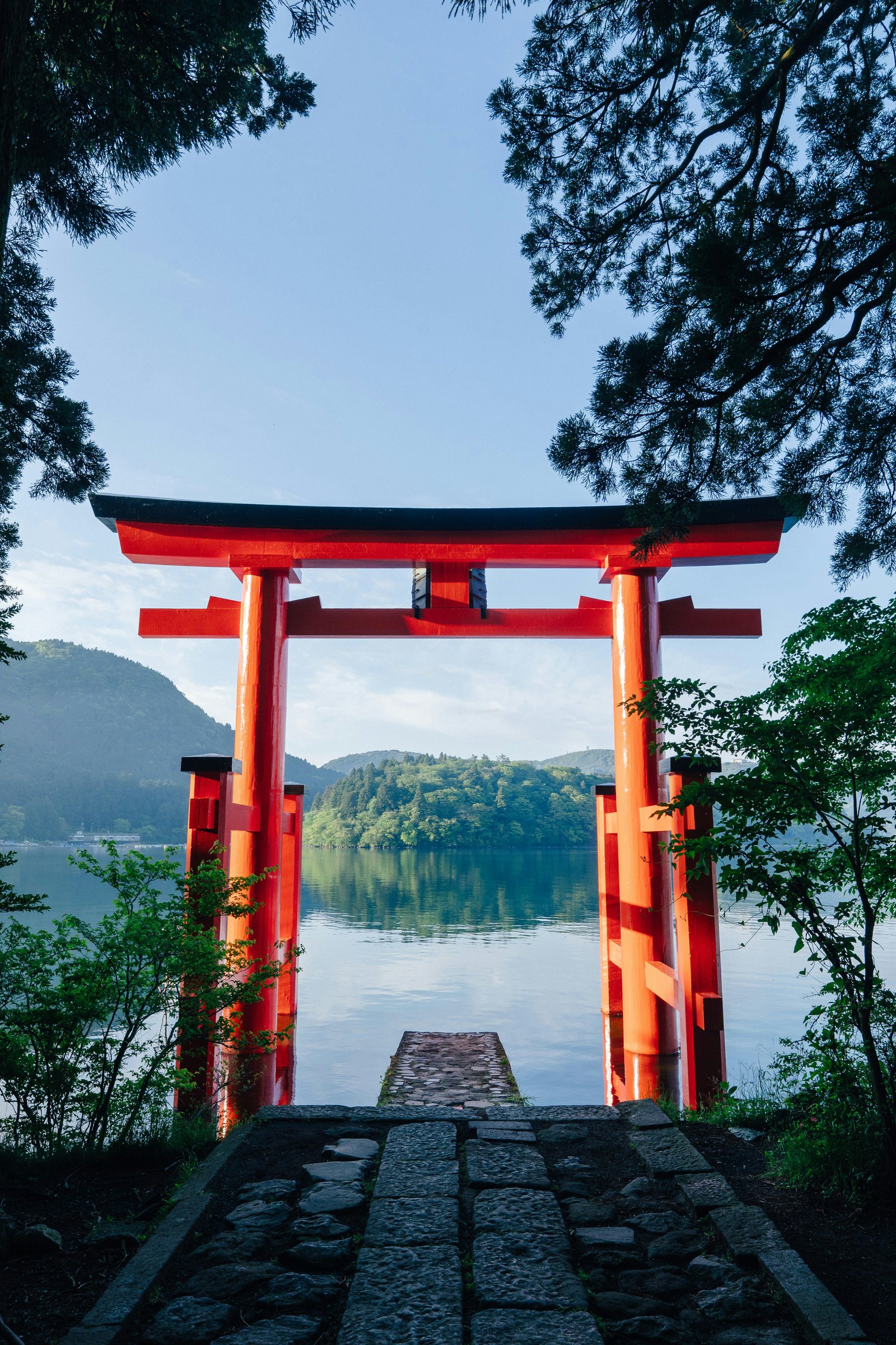 Red torii gate framing Lake Ashi with mountains beyond in Hakone