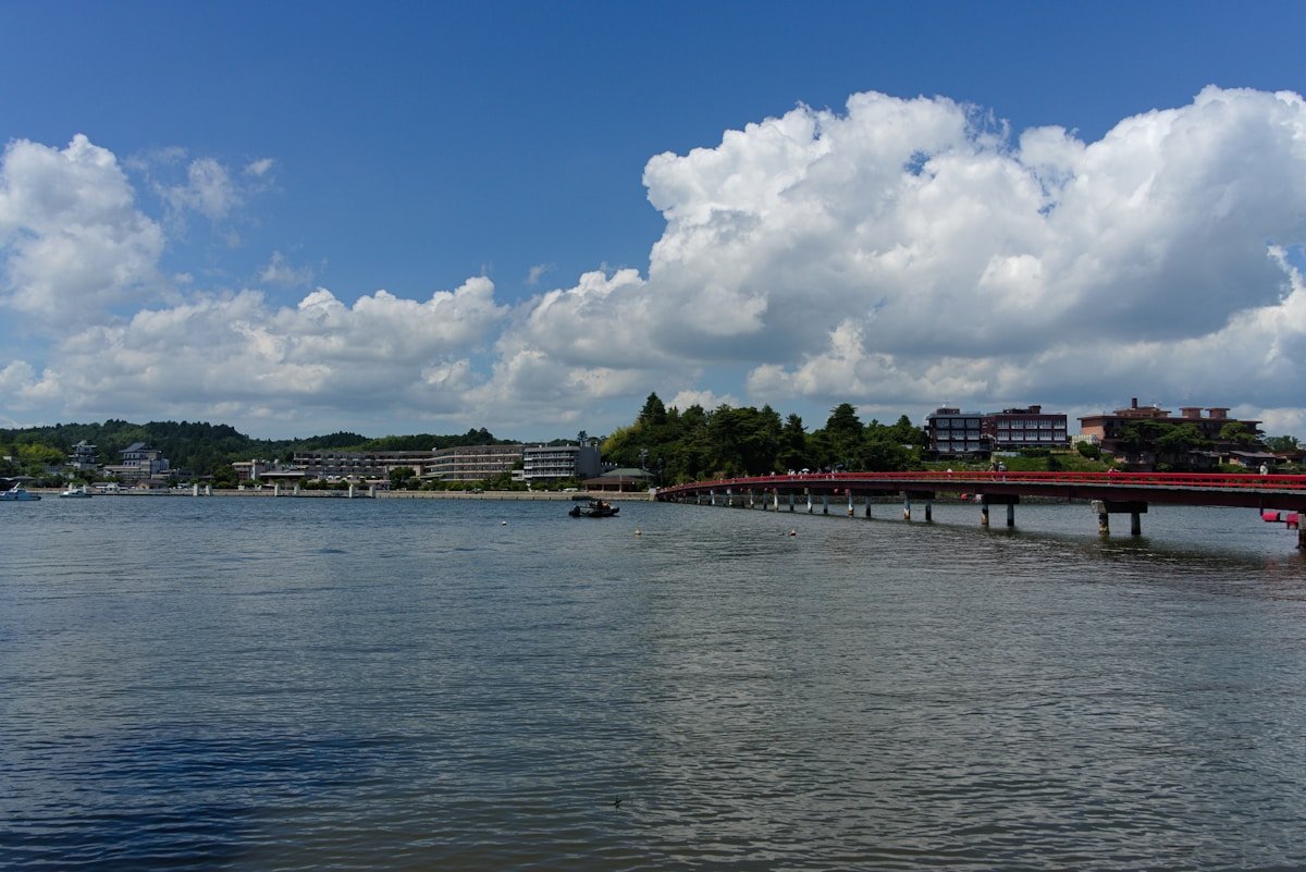 Red bridge over calm coastal water with resort hotels and pine trees in the Matsushima area, Miyagi, Japan