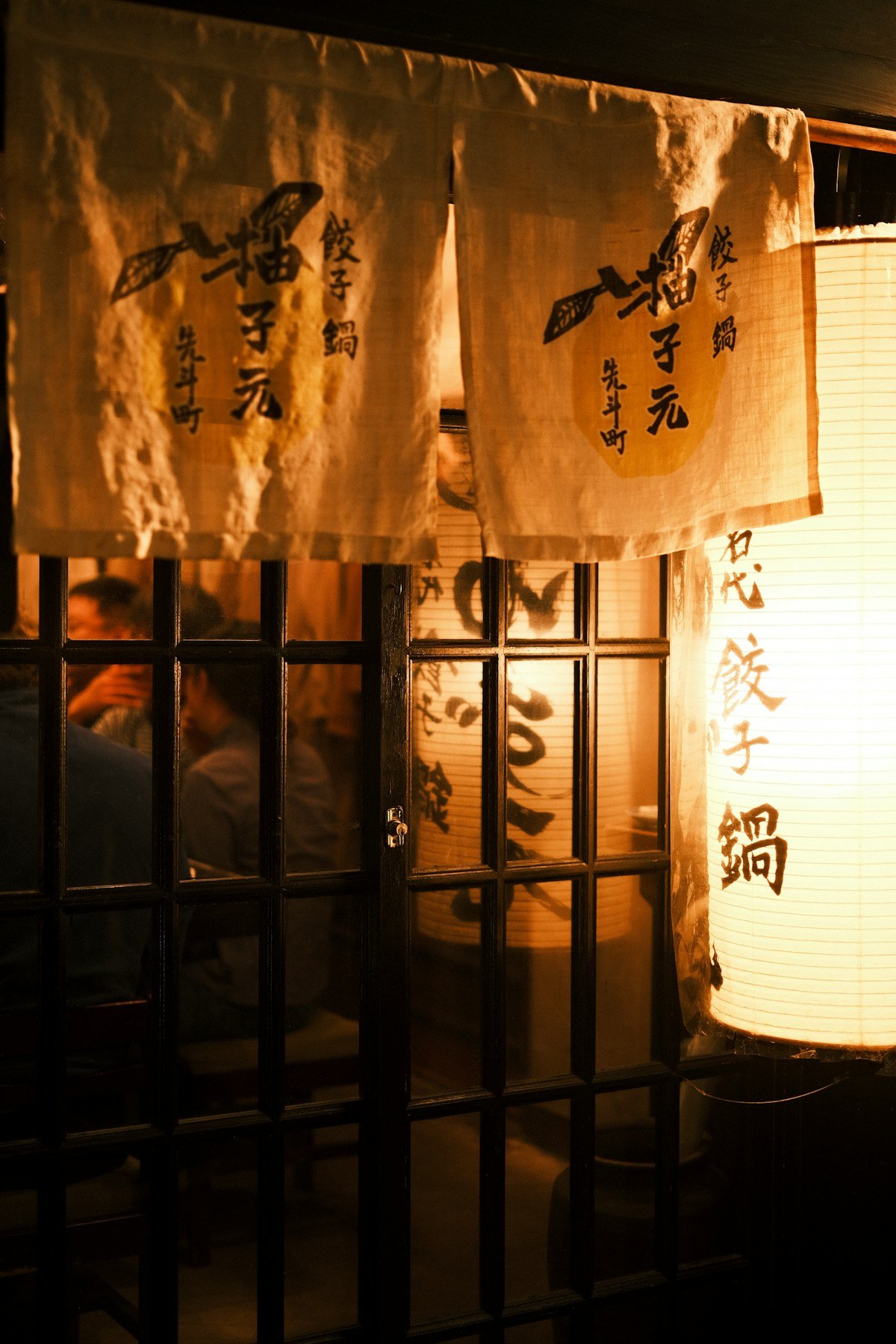 Japanese restaurant entrance with paper lanterns and noren curtains at night