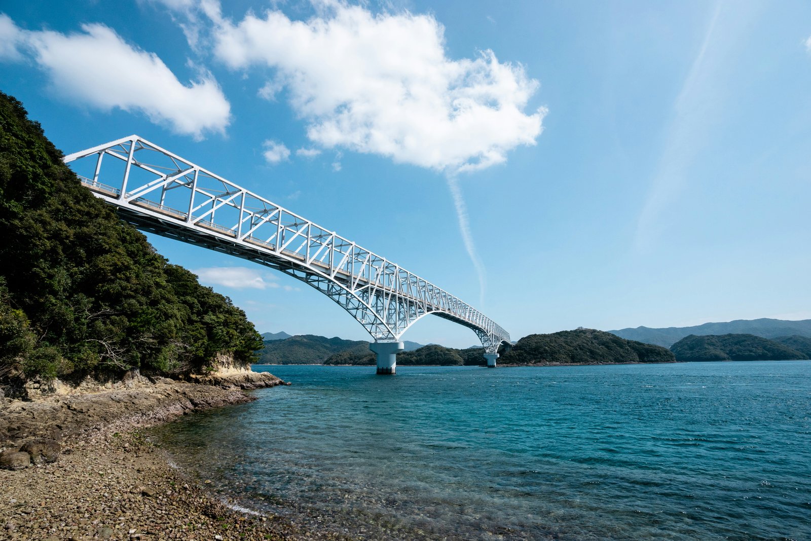 White arch bridge spanning the turquoise coastal waters of Nagasaki prefecture