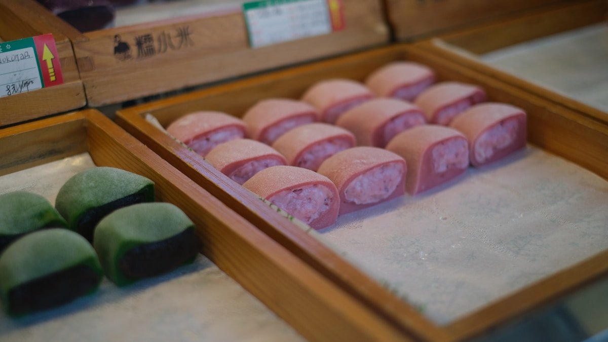 Pink and green Japanese mochi sweets displayed on a market stall