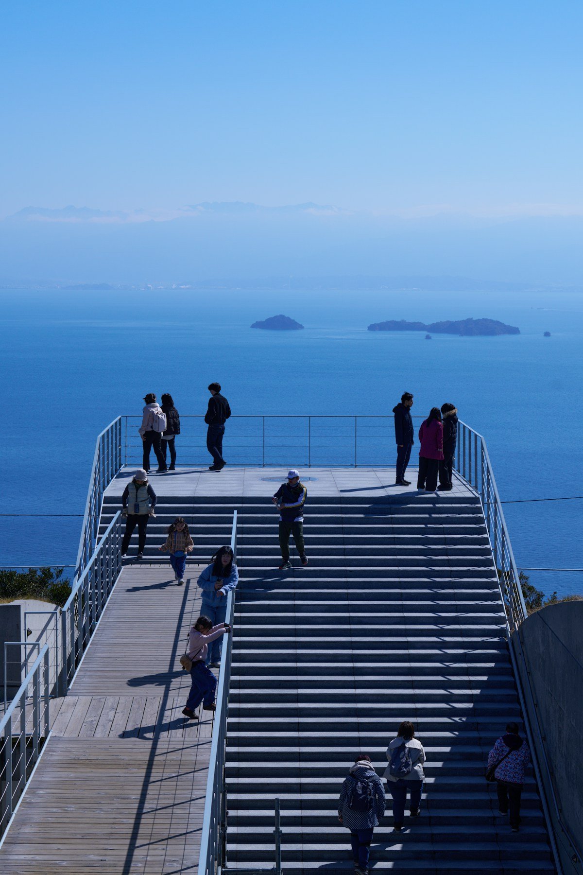 Visitors on an observation deck overlooking an island-dotted bay in Japan