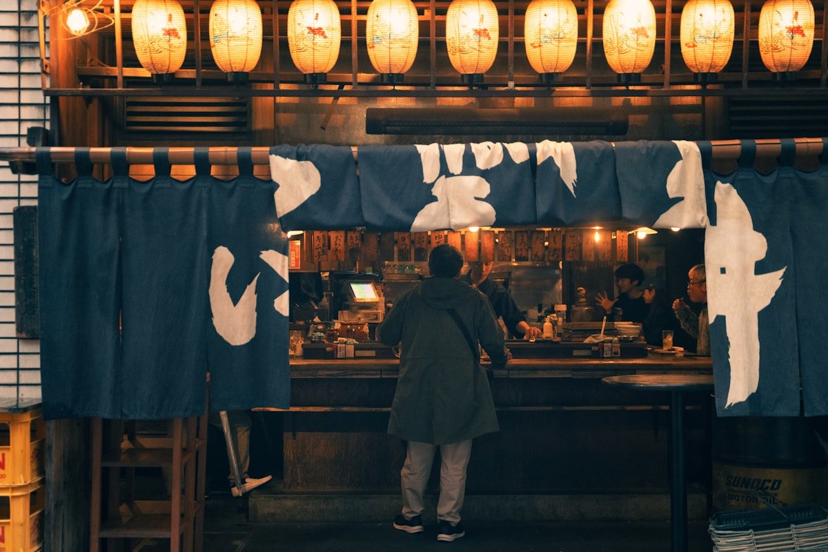 Traditional Japanese izakaya at night with glowing paper lanterns and noren curtains