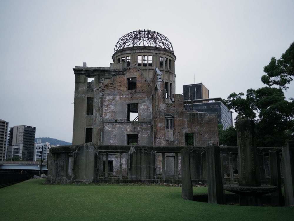 The Atomic Bomb Dome seen from the grass beside the river on an overcast day