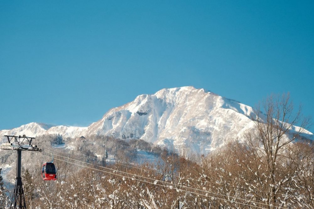 Red gondola cabin and a snow-covered peak in the Japanese Alps