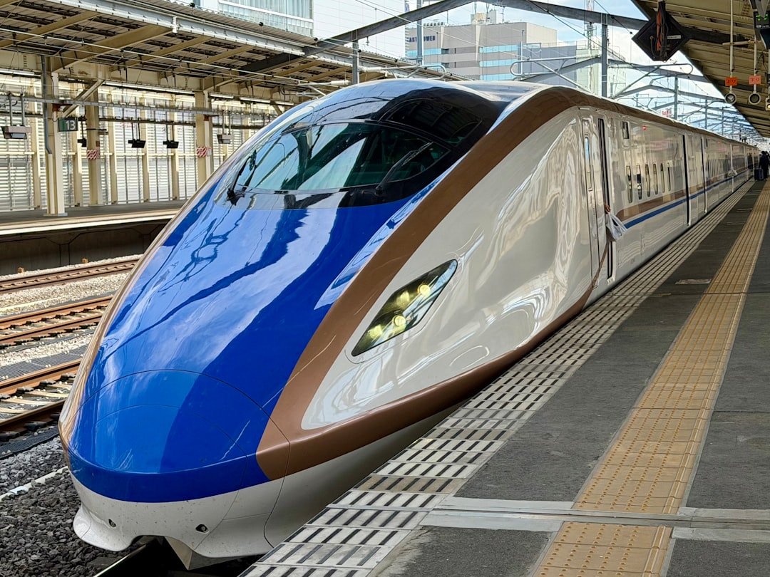 A blue and gold E7 series shinkansen bullet train at a Japanese station platform