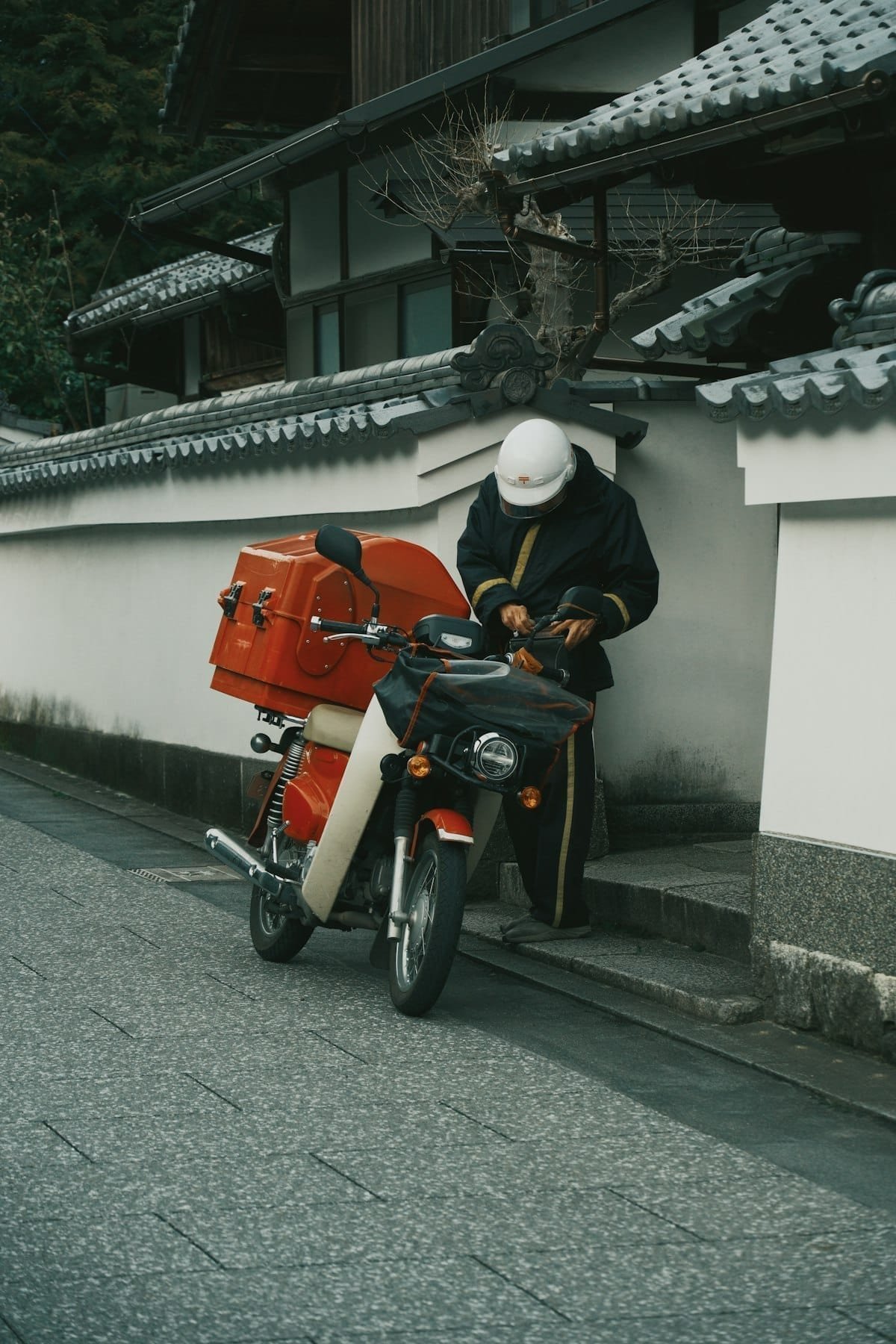 Delivery worker with red cargo box on motorbike in Arashiyama, Kyoto, Japan