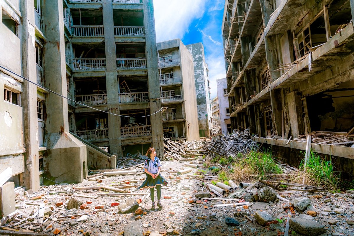 Gunkanjima abandoned island ruins in Nagasaki — a person surveys the collapsed buildings of the former coal mine settlement