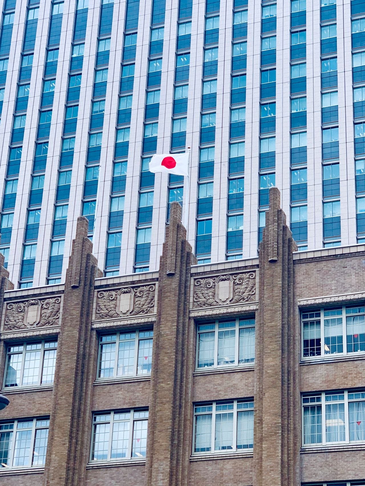 Japanese flag flying above a brick and glass government building in Chiyoda, Tokyo