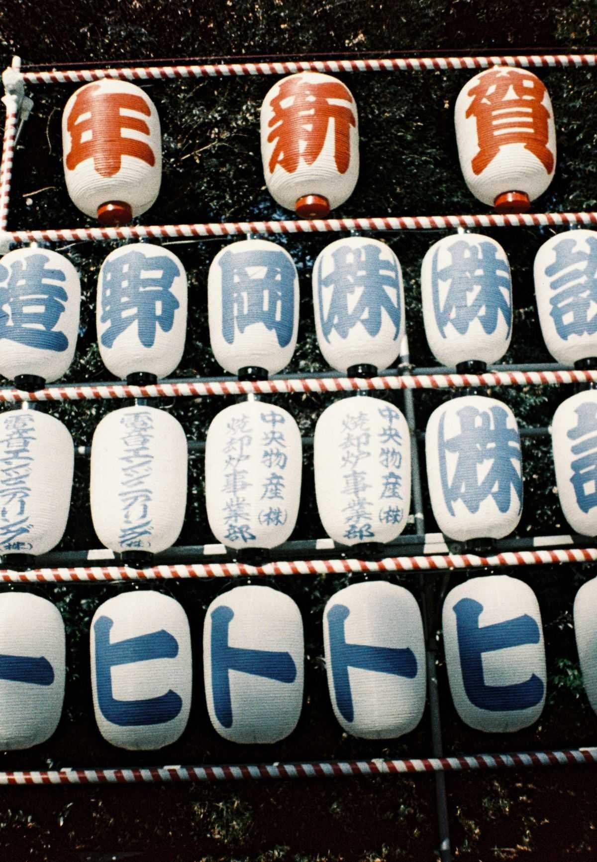 Traditional Japanese paper lanterns with kanji text displayed at an outdoor festival