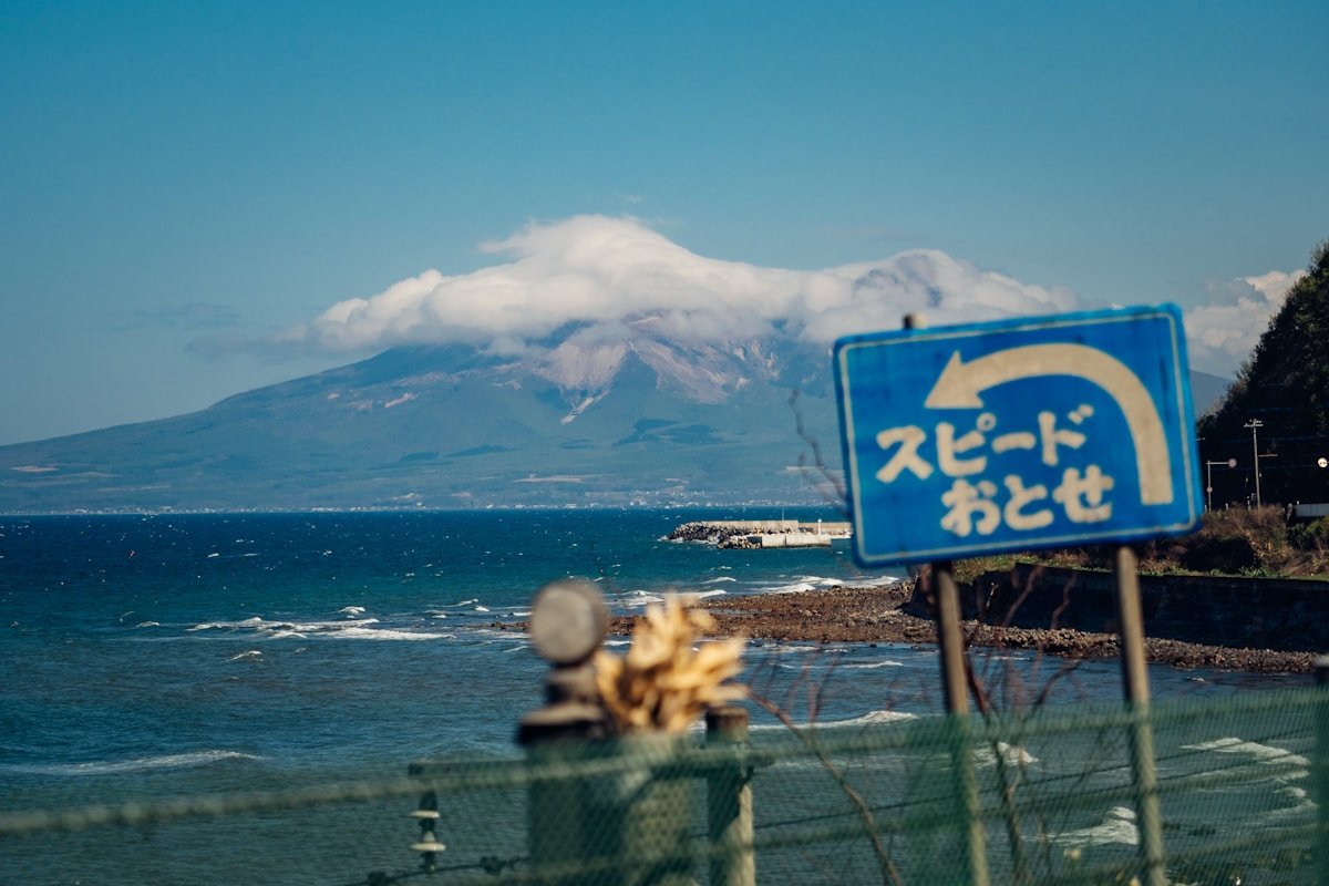 Japanese coastal road sign with ocean and mountain backdrop — natural disaster safety in Japan