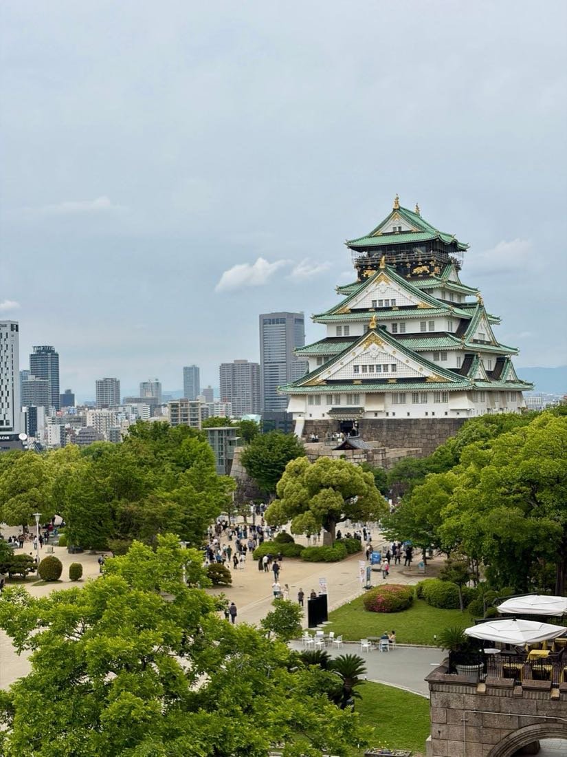 Osaka Castle above green parkland with the city skyline behind