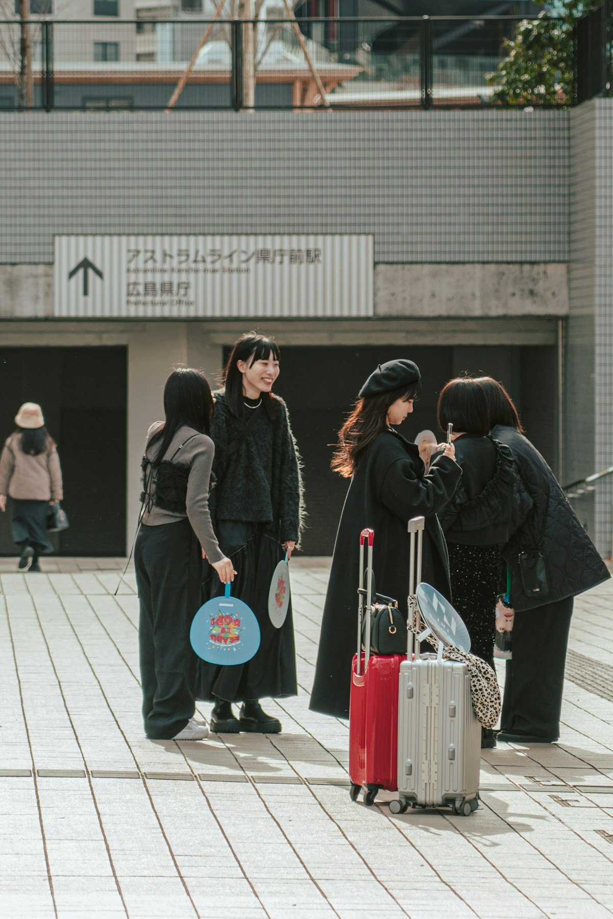 Travellers with luggage outside Hiroshima station, Japan