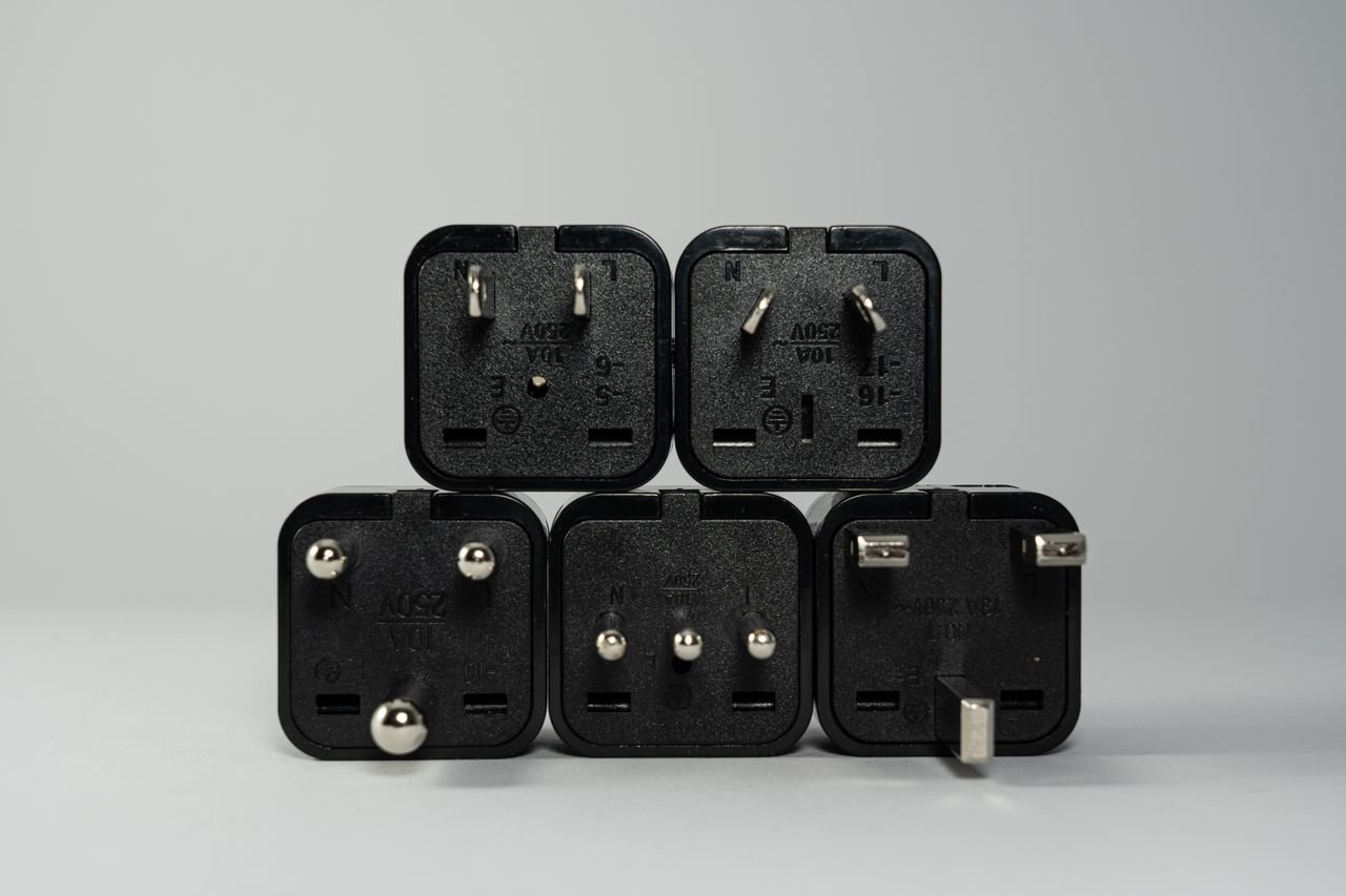 Set of black travel plug adapters with different pin layouts used when travelling abroad