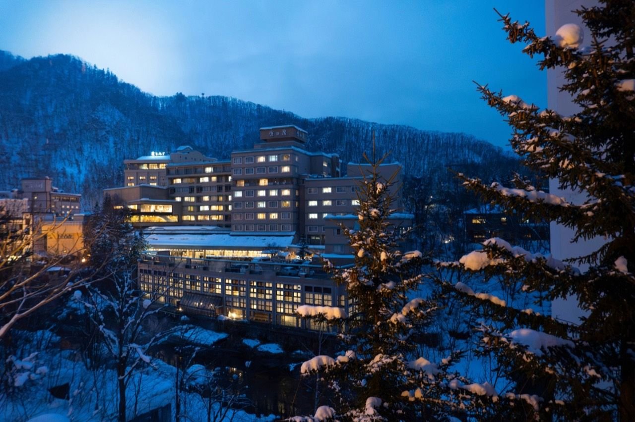 Snowy mountain resort building with illuminated windows, Jōzankei Sapporo Hokkaido Japan