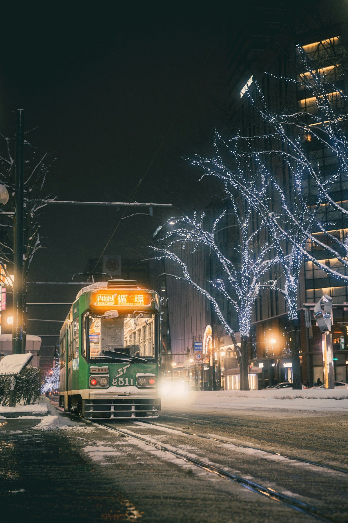 Sapporo tram running through snow-covered streets at night